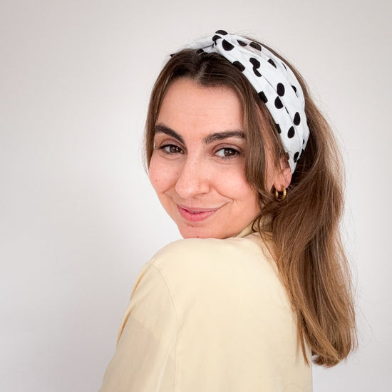 frontalansicht einer frau, die ein weißes haarband mit schwarzen punkten trägt