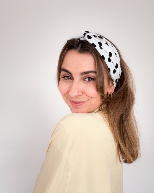 frontalansicht einer frau, die ein weißes haarband mit schwarzen punkten trägt