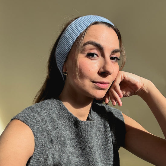 eine frau schaut in die kamera und trägt ein stirnband aus merinowolle in der farbe blau