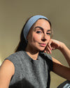 eine frau schaut in die kamera und trägt ein stirnband aus merinowolle in der farbe blau