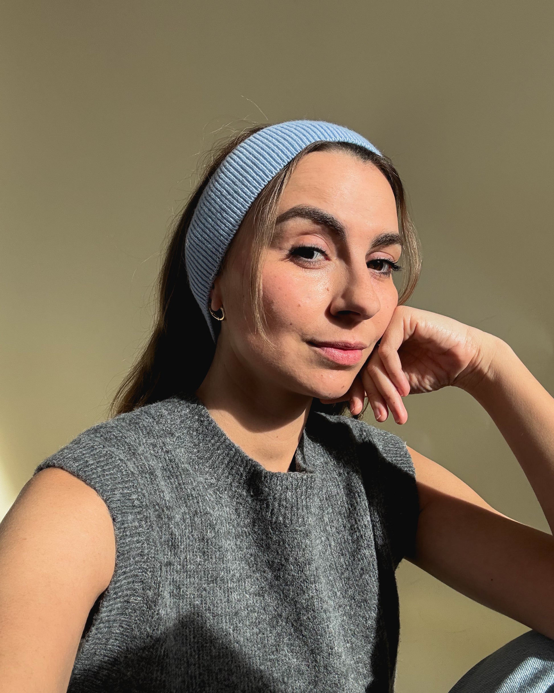 eine frau schaut in die kamera und trägt ein stirnband aus merinowolle in der farbe blau
