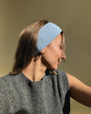 eine frau schaut in die kamera und trägt ein stirnband aus merinowolle in der farbe blau