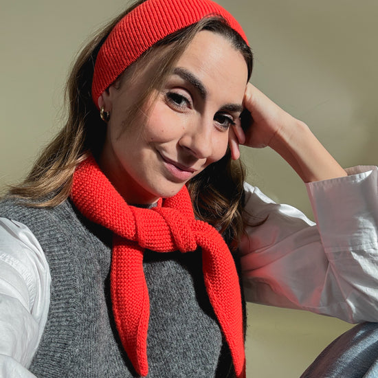 eine frau trägt ein haarband und ein minischal aus merinowolle in der farbe orange