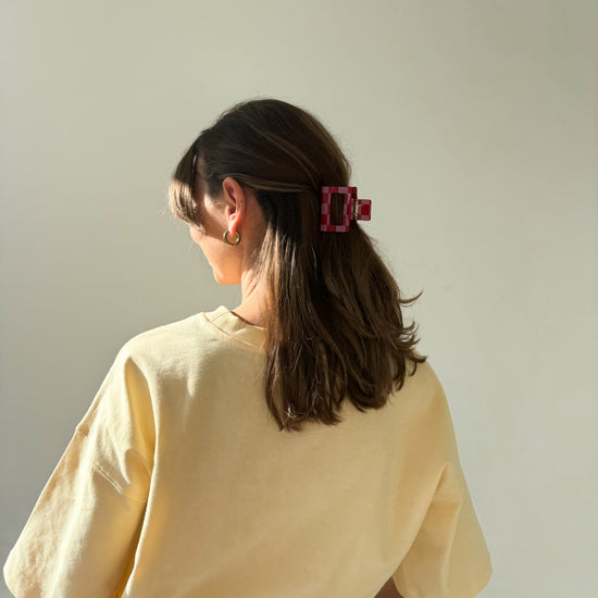 eine frau trägt eine haarklammer aus acetat in der farbe pink/rot