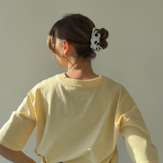 rückansicht einer frau, die ein weißes haarband mit schwarzen punkten trägt