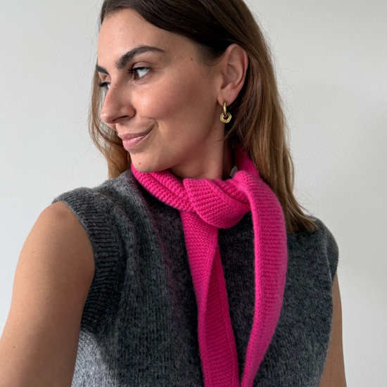 eine frau trägt einen mini schal in pink aus merinowolle