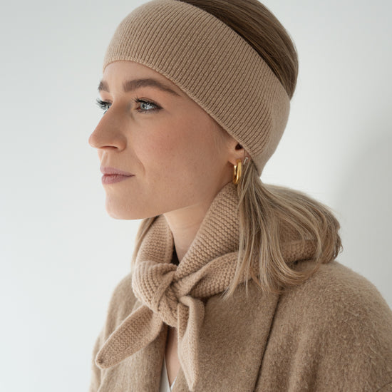 eine frau trägt ein stirnband und einen minischal aus merinowolle in beige